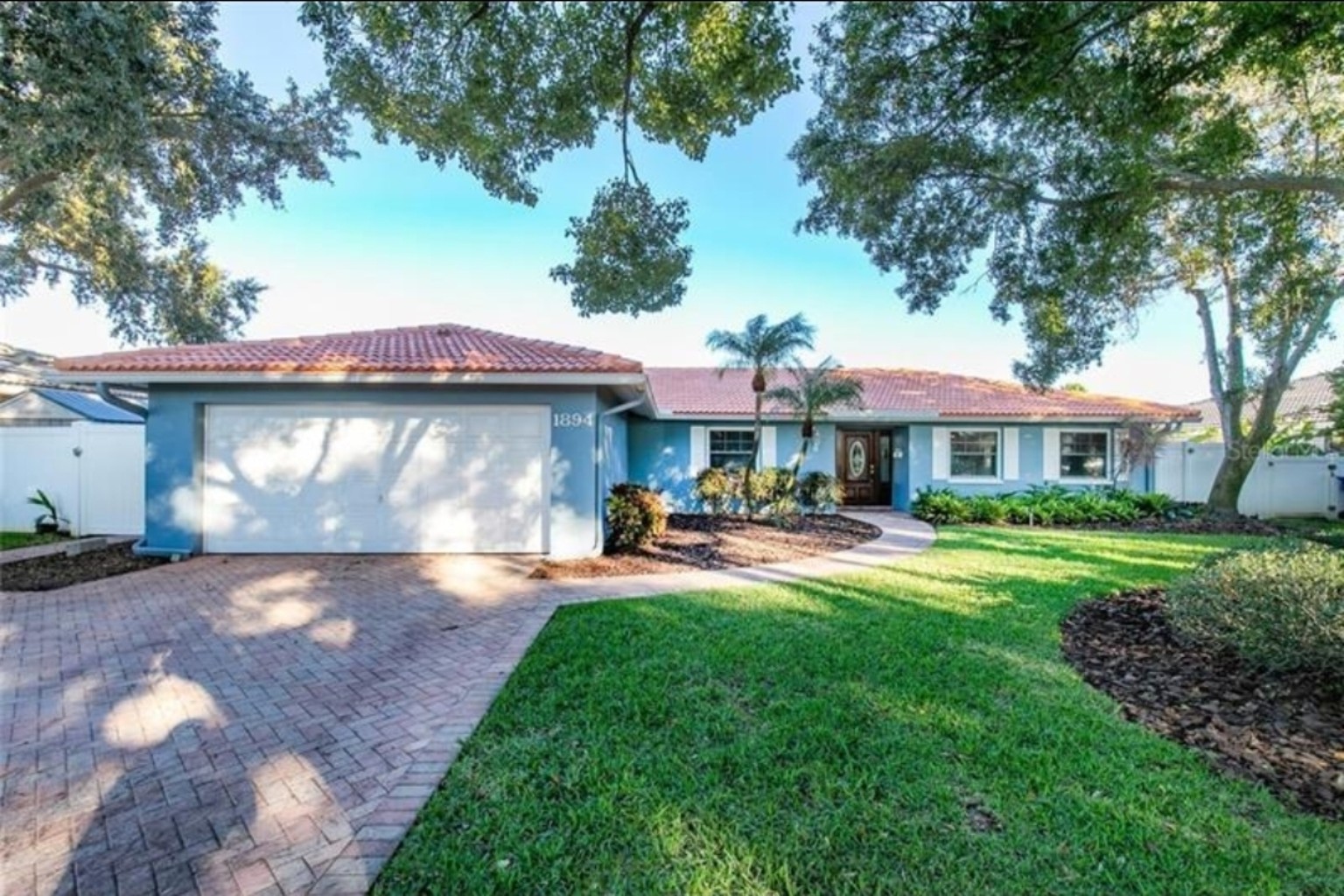 Front exterior of the blue Tanglewood home with a tile roof and landscaped yard